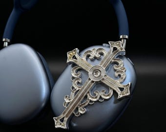 May include: Over-ear headphones in a matte blue finish featuring a large, ornate silver-toned cross emblem attached to the exterior of the right ear cup. The cross has intricate scrollwork details and a polished metallic surface.