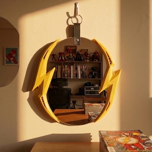 May include: A circular mirror with a yellow lightning bolt design. The mirror is suspended from a wall by a leather strap and keyring. A stack of comic books rests on a wooden table.