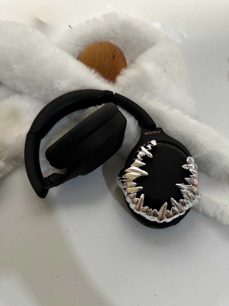 May include: Black wireless headphones with a silver, sharp, tooth-like design on one earcup. The headphones have the word "SONY" printed on the side.