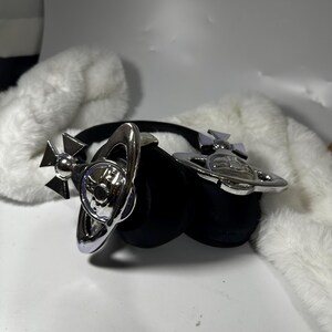 May include: A pair of black headphones with silver orb-shaped accents. The headphones have a black headband and earcups. The orb accents are detailed with a star and a circle.