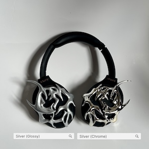 May include: Two pairs of black Sony headphones with silver decorative accents. One pair has a glossy finish, the other a chrome finish. The headphones have a black headband and earcups. The text "SONY" is visible on the earcups.
