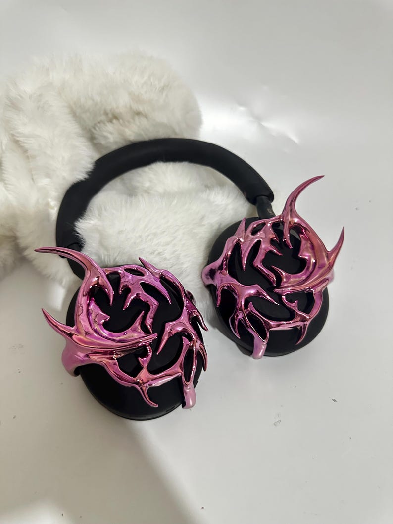 May include: Pink and black headphones with a decorative, metallic, flame-like design on the earcups.
