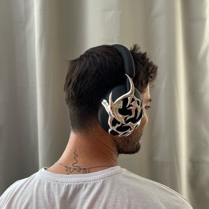 May include: A person wearing black headphones with a silver decorative design. The headphones are over the ears and have a black headband.