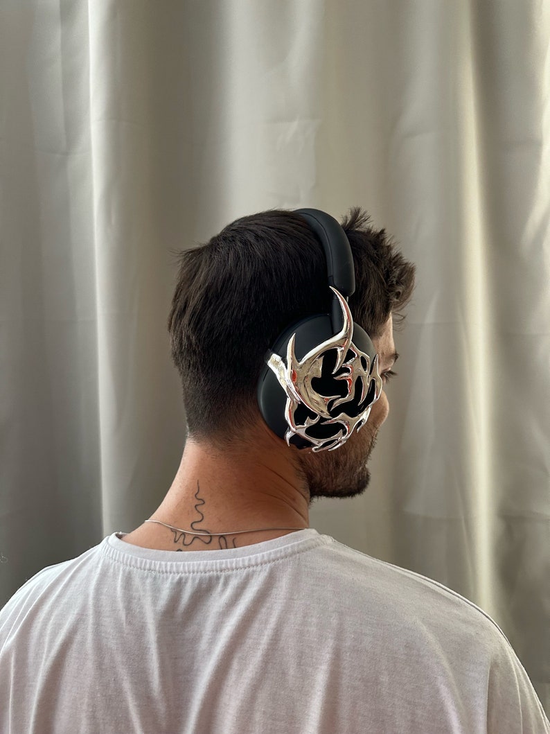 May include: A person wearing black headphones with a silver decorative design. The headphones are over the ears and have a black headband.