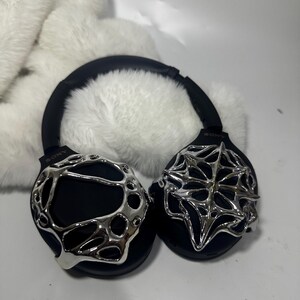 May include: Black over-ear headphones with silver decorative accents. The headphones have a black headband and earcups, with intricate silver designs on the earcups. The Sony logo is visible on the headphones.
