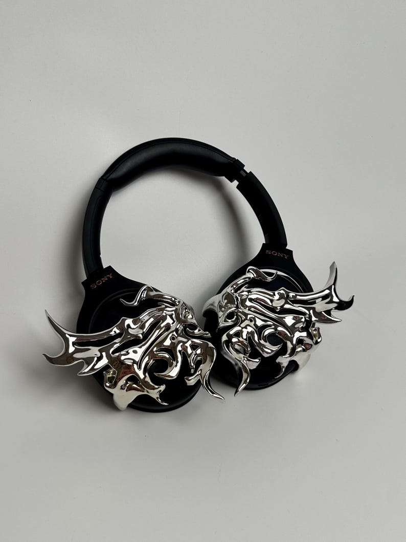 May include: Black Sony headphones with silver, flame-like embellishments on the earcups. The headphones have a padded headband and earcups for comfort. The silver accents add a unique, artistic flair to the headphones.