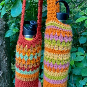 May include: Two crocheted water bottle holders with colorful stripes in shades of orange, green, brown, and pink. The holders have long straps for carrying.