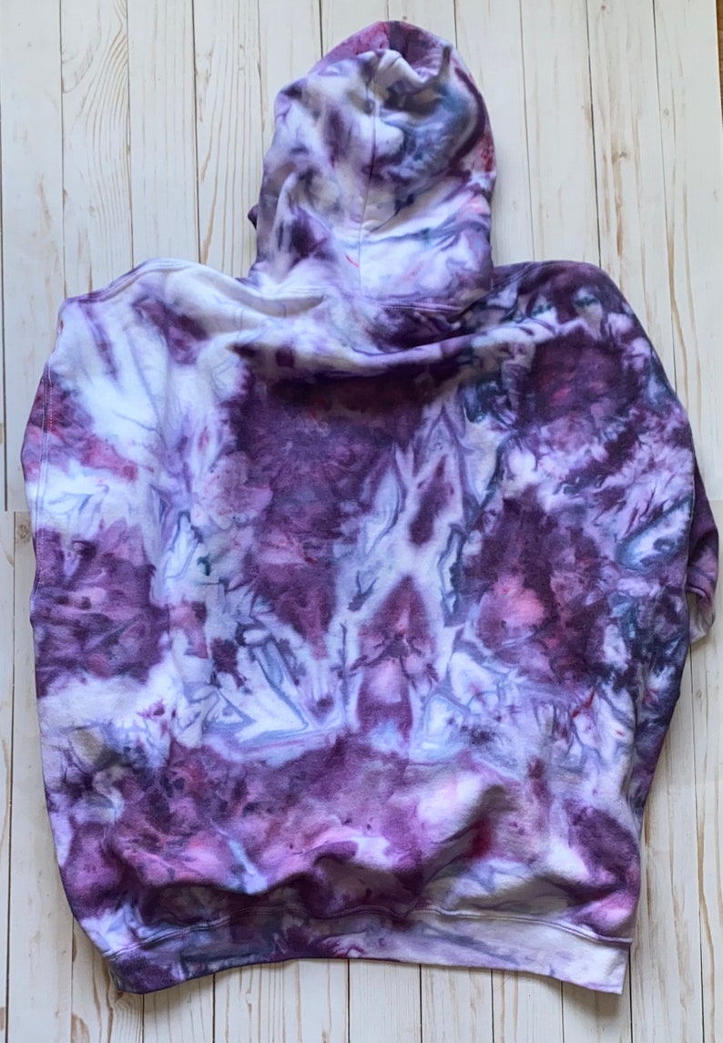 May include: Purple, white, and gray tie-dye hoodie with a hood. The hoodie is made of a soft, comfortable fabric.