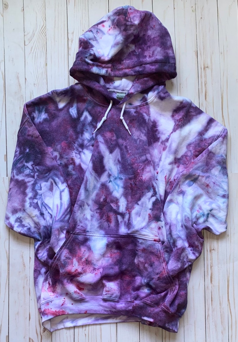 May include: Purple tie-dye hoodie with a white drawstring and a kangaroo pocket.