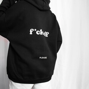 May include: Black hooded sweatshirt with the text "f*ck off" in white letters on the back. The text "PLEASE" is printed in white below the main text.