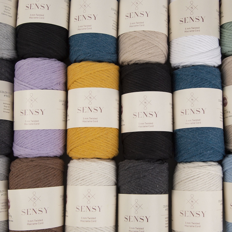 May include: A collection of 10 spools of 3mm twisted macrame cord in various colors, including black, white, brown, gray, blue, and yellow. Each spool is labeled with the brand name "SENSY" and the cord thickness.