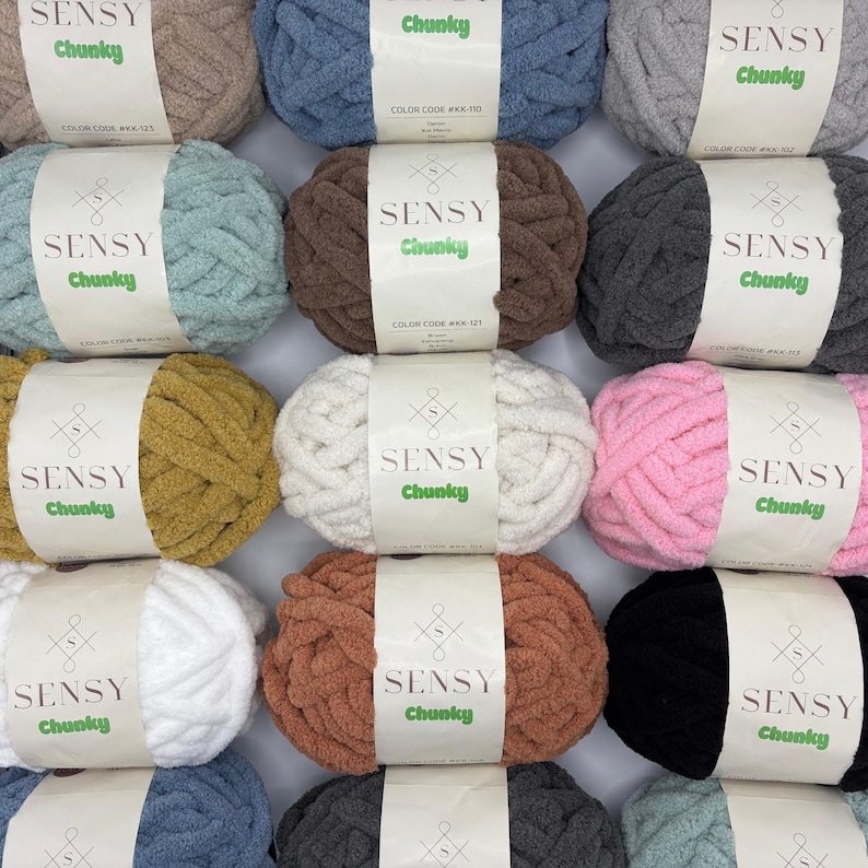 Puede incluir: Surtido de 12 ovillos de hilo Sensy Chunky en varios colores, incluyendo beige, azul, marr&oacute;n, gris, verde, amarillo mostaza, rosa, blanco, naranja, negro y azul claro. Cada ovillo tiene una etiqueta con el nombre de la marca "Sensy Chunky" y un c&oacute;digo de color.
