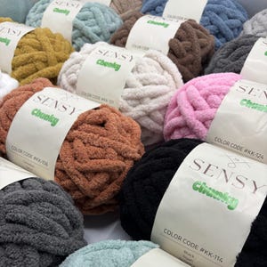Puede incluir: Una variedad de ovillos de lana de colores con el nombre de la marca "SENSY Chunky" y c&oacute;digos de color impresos en las etiquetas. La lana es suave y esponjosa, perfecta para tejer al crochet o tejer.