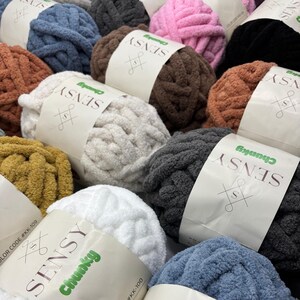 Puede incluir: Una variedad de ovillos de lana de colores con el nombre de la marca "SENSY Chunky" impreso en las etiquetas. La lana es de textura gruesa y est&aacute; disponible en colores como blanco, gris, marr&oacute;n, rosa, azul y amarillo.