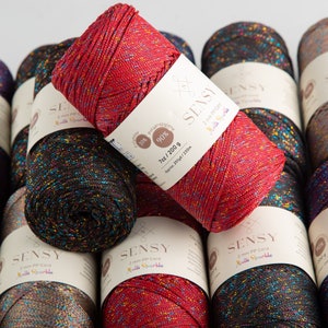 Puede incluir: Primer plano de varios carretes de hilo rojo, negro y marr&oacute;n con purpurina plateada. El hilo est&aacute; etiquetado como "SENSY 2 mm PP Cord Multi Sparkle" y "7oz/200g Approx. 251yd/230m".