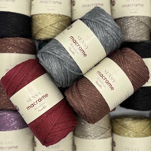 May include: Image of multiple macrame cord spools in shades of grey, burgundy, and brown. Each spool features a label with the text "SENSY macrame PP Cord 5 mm Sparkle".