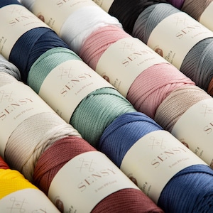 May include: A collection of colorful spools of 3 mm PP cord, each wrapped with a label that reads "SENSY". The cord colors include shades of blue, pink, green, and neutral tones. Each spool is labeled with the weight of 250 g.