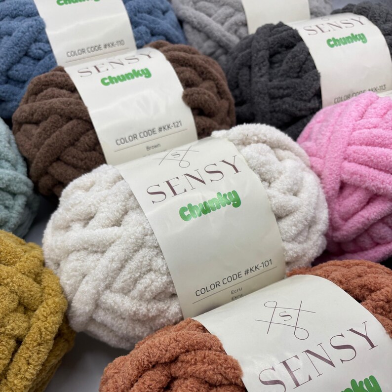 Puede incluir: Surtido de ovillos de lana de colores etiquetados como "SENSY Chunky" con c&oacute;digos de color y nombres. La lana es suave y esponjosa, perfecta para tejer al crochet o tejer.