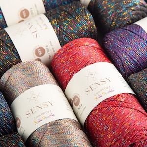 Puede incluir: Primer plano de carretes de hilo de colores con un acabado brillante. Los carretes est&aacute;n etiquetados con "SENSY 2 mm PP Cord Multi Sparkle" y tienen un contenido de polipropileno del 90%. Cada carrete pesa 200 g y tiene una longitud de 250 m.