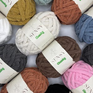Puede incluir: Una variedad de ovillos de lana de colores, cada uno con una etiqueta que dice "SENSY Chunky" y un c&oacute;digo de color. La lana es gruesa, esponjosa y texturizada.