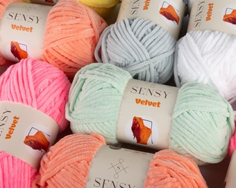 May include: A variety of colorful yarn skeins in shades of pink, orange, yellow, green, and white. The yarn is a soft, plush velvet texture. Each skein has a label that reads "Sensy Velvet".