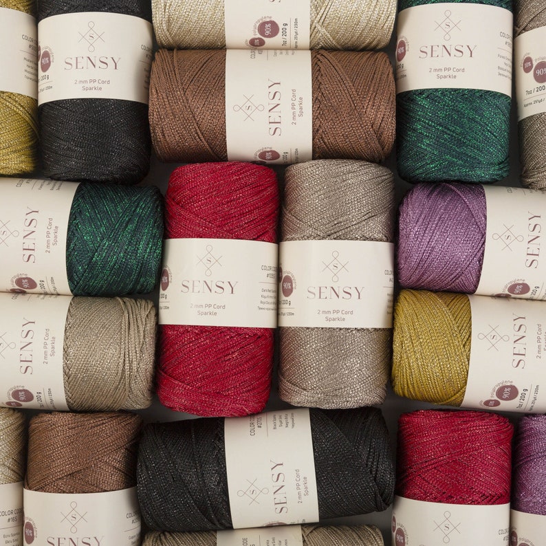 Peut inclure: Une collection de fil en cordon PP de 2 mm dans diff&eacute;rentes couleurs, notamment noir, vert, rouge, or et beige. Chaque bobine porte une &eacute;tiquette avec le nom de la marque "SENSY" et le texte "2 mm PP Cord Sparkle".