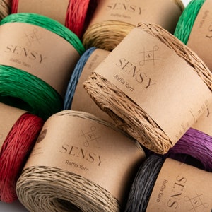 May include: Assortment of colorful raffia yarn spools with brown paper labels that say "SENSY Raffia Yarn".