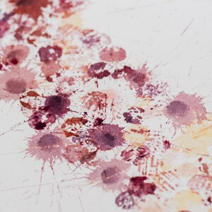 May include: A white background with a series of pink, red, and orange watercolor splatters. The splatters are arranged in a diagonal line from the top left corner to the bottom right corner of the image.
