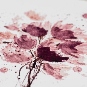 May include: Abstract watercolor painting of pink and purple flowers with splattered paint on a white background.