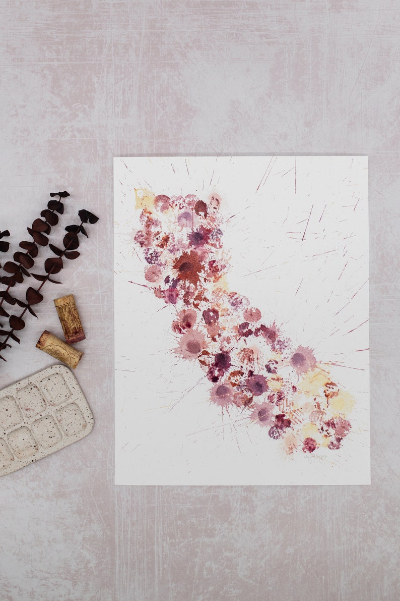 May include: A white sheet of paper with a splatter painting of red, pink, and yellow paint. The paint is in the shape of a long, thin cloud.