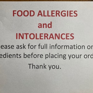 May include: A white sign with red text that reads "FOOD ALLERGIES and INTOLERANCES. Please ask for full information on ingredients before placing your order. Thank you."
