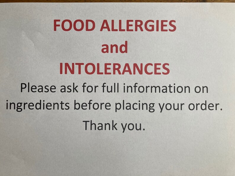 May include: A white sign with red text that reads "FOOD ALLERGIES and INTOLERANCES. Please ask for full information on ingredients before placing your order. Thank you."