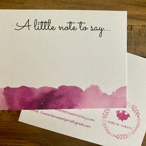 May include: A white card with the text "A little note to say..." in black cursive. The bottom of the card has a watercolor design in shades of purple. The back of the card has a floral design with the text "Sweete Sweets" in a circle.