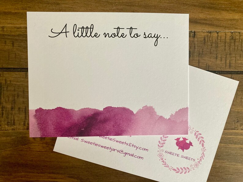 May include: A white card with the text "A little note to say..." in black cursive. The bottom of the card has a watercolor design in shades of purple. The back of the card has a floral design with the text "Sweete Sweets" in a circle.