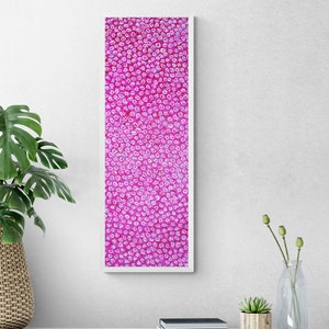 Könnte beinhalten: Ein hohes, rechteckiges Wandbild mit einem leuchtend magentafarbenen Hintergrund, der dicht mit kleinen, sich wiederholenden weißen Spiralmustern bedeckt ist. Das Kunstwerk ist in einen schlichten, dünnen weißen Rahmen gefasst, der für eine klare Optik sorgt.