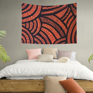 May include: A white bed with a patterned tapestry hanging on the wall behind it. The tapestry is black and orange with geometric designs. There are pillows on the bed and a wooden headboard.
