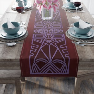 May include: A burgundy table runner with a geometric pattern in a light purple color. The pattern is a repeating design of squares, triangles, and diamonds.