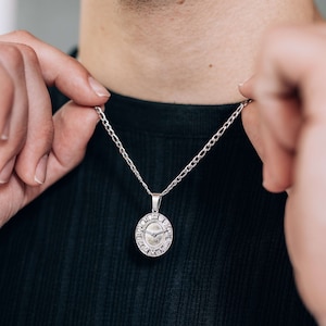 May include: A silver chain necklace with a round pendant featuring Roman numerals and a clock face.