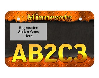 May include: Orange and black metal license plate with the word "Minnesota" and the letters "AB2C3" in gold. The plate has a space for a registration sticker.