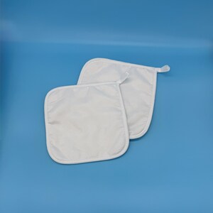 May include: Two white square oven mitts with rounded corners and a loop for hanging. The mitts are made of a smooth, solid white material and are set against a blue background.