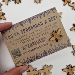 May include: A brown card with the text "You've Sponsored a Bee!" and a QR code. The card is surrounded by small wooden bee cutouts.
