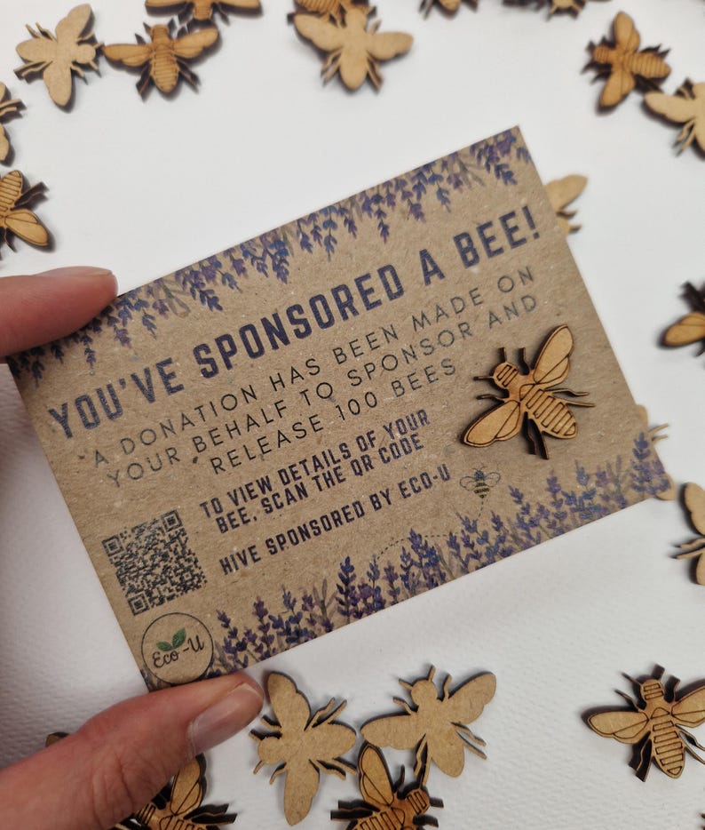 May include: A brown card with the text "You've Sponsored a Bee!" and a QR code. The card is surrounded by small wooden bee cutouts.
