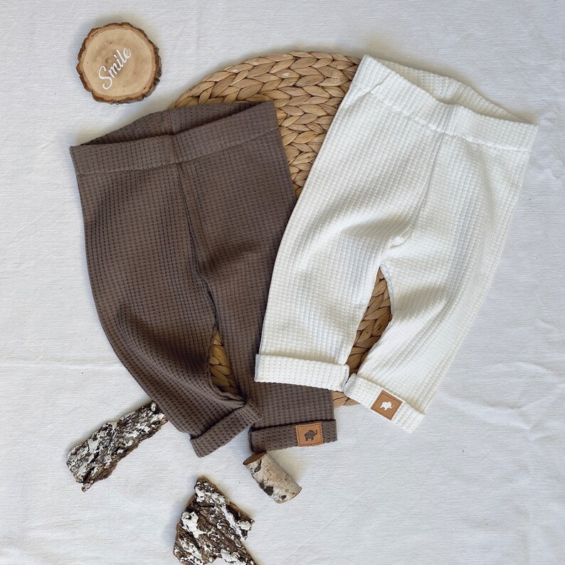 May include: Two pairs of waffle knit leggings, one brown and one white. Both pairs have a small leather patch with a buffalo silhouette on the leg.