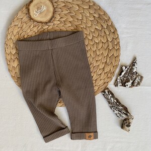 May include: Brown waffle knit leggings with a small brown leather patch on the bottom of the right leg.