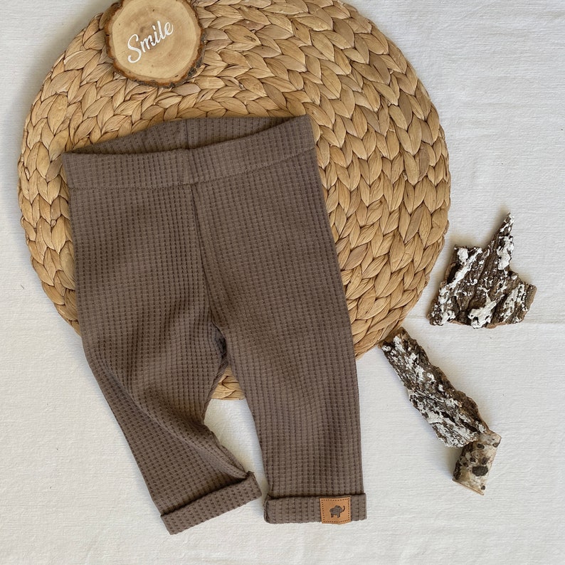 May include: Brown waffle knit leggings with a small brown leather patch on the bottom of the right leg.