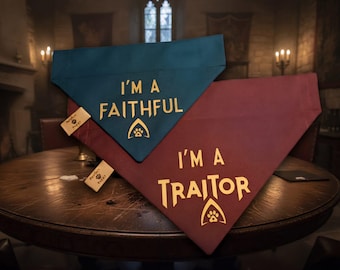 May include: Two triangular pet bandanas, one teal and one maroon, featuring gold lettering. The teal bandana reads I'M A FAITHFUL with a paw print icon, and the maroon bandana reads I'M A TRAITOR with a paw print icon. Each has a small tag.