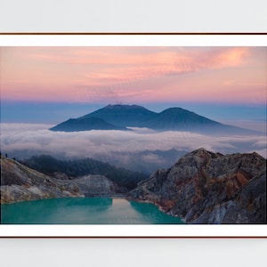 May include: A panoramic view of a volcanic landscape with a turquoise lake in the foreground. The mountains are shrouded in mist and the sky is a soft pink and blue.