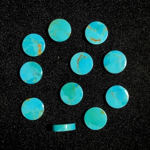 以下が含まれることがあります： 黒い表面に並べられた、茶色の筋が入った丸いターコイズのcabochonsが12個あります。