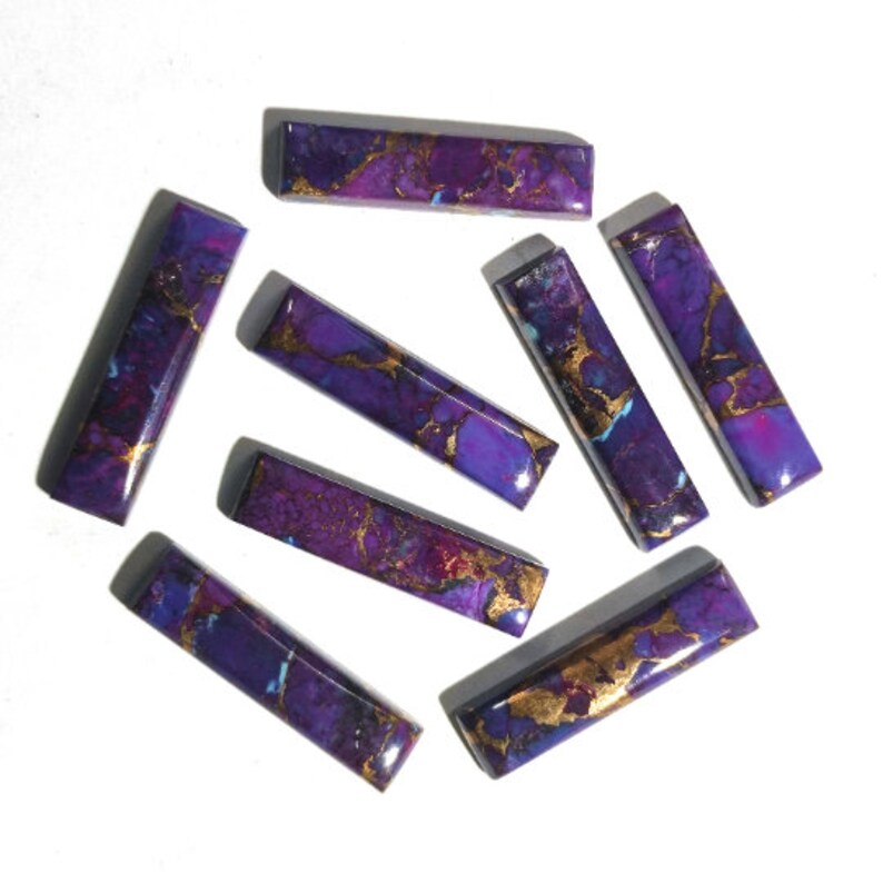 K&ouml;nnte beinhalten: Acht rechteckige Cabochons in Lila und Gold. Die Cabochons haben ein marmoriertes Muster mit violetten und goldenen Wirbeln.
