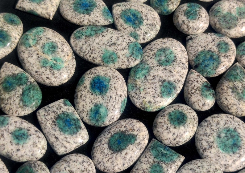 May include: A collection of polished, oval-shaped, blue and white speckled stones. The stones have a mottled appearance with blue and white speckles.